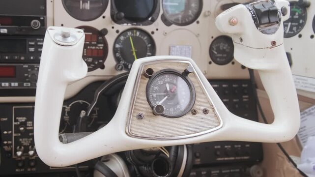 Close-up view of aircraft cockpit controls and analog flight instruments inside small airplane cabin, showcasing aviation technology, navigation systems and pilot workspace.
