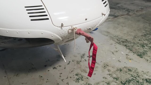 Protective red remove before flight ribbon attached to aircraft exterior component, emphasizing aviation safety procedures and preflight inspection operations.