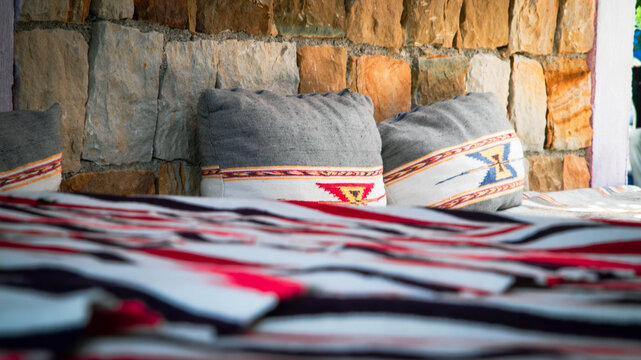 Handmade Moroccan cushions against a stone wall, highlighting textures and a warm traditional atmosphere.