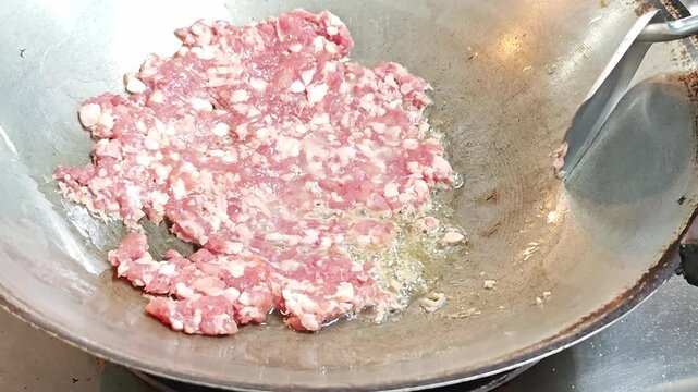 Close-up of minced pork frying during cooking process.