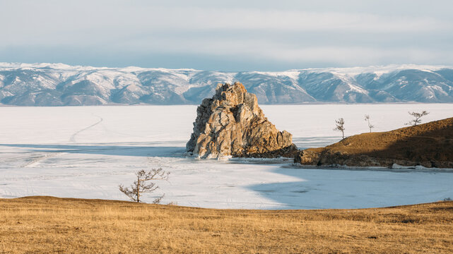 Scenic winter view of Shamanka Rock on frozen Lake Baikal near Khuzhir, Olkhon Island, Irkutsk Oblast, Russia, with snow, ice and distant mountains