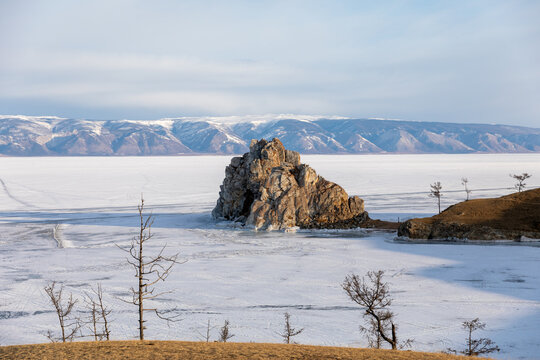 Winter landscape with Shamanka Rock rising from the frozen surface of Lake Baikal near Khuzhir village, Olkhon Island, Irkutsk Oblast, Russia under clear sky