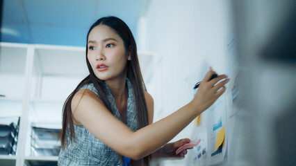 Businesswoman writes on charts with notes in a modern office, showing planning, analysis, teamwork,...