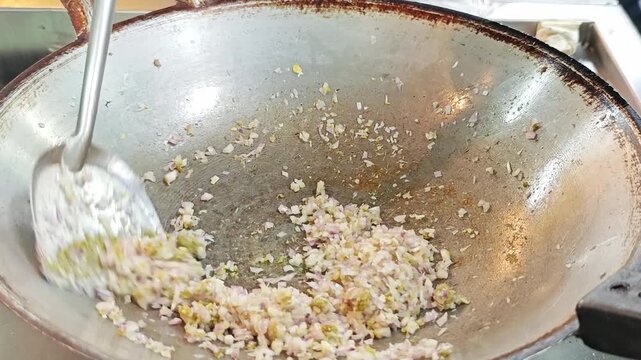 Saut&eacute;ing minced shallots and garlic in a hot wok pan.