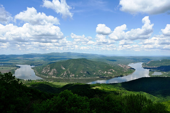 the riverbend of the Danube river at Zebegeny village, and Nagymaros, Hungary. lush green hills in the background. popular summer holiday destination. smooth calm water surface. blue sky, white clouds