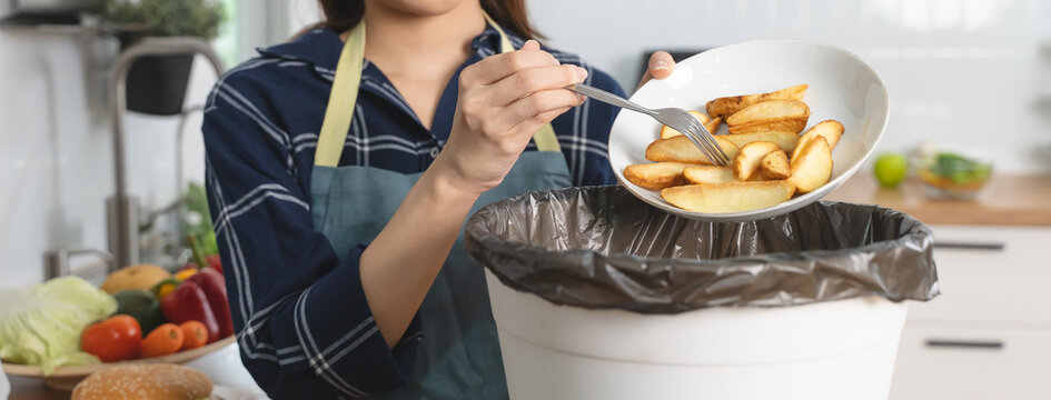 woman putting waste from food into bin trash in the kitchen