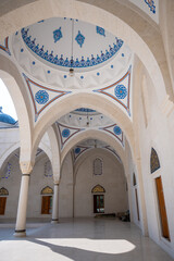 Fototapeta premium The expansive, bright interior of Mosque of Namazgah in Tirana, Albania with multiple white arches, sturdy pillars, and a beautifully decorated dome featuring Islamic art, bathed in soft daylight.