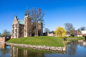 Obraz premium Rosenborg Castle in Copenhagen, Denmark, overlooks a tranquil moat on a sunny day.