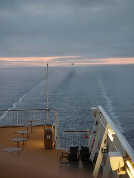 Empty ferry deck with sea wake under cloudy twilight sky