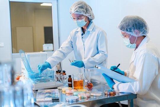 Two scientists in lab coats work at a lab bench. Asian scientists or researchers team working on medical and pharmaceutical development in a modern laboratory.