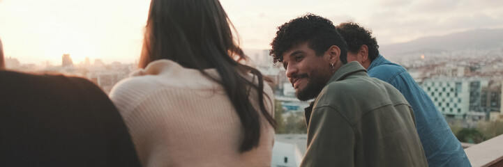 Naklejka premium Guys and girls at the party, looking at the beautiful views and talking standing on the terrace, friendly party holiday at sunset. Panoramic