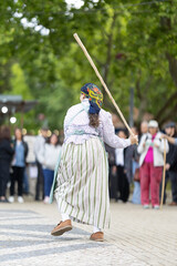 Naklejka premium Dancer performs traditional routine with stick during outdoor event near crowd in the afternoon light