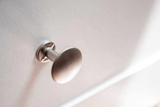 Metal drawer knob on white cabinet surface