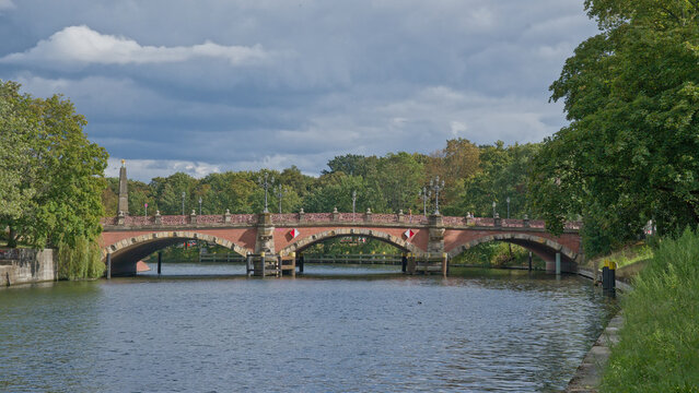 River Spree with Luther historical brick arch bridge and green trees on the borders in Berlin, Germany 