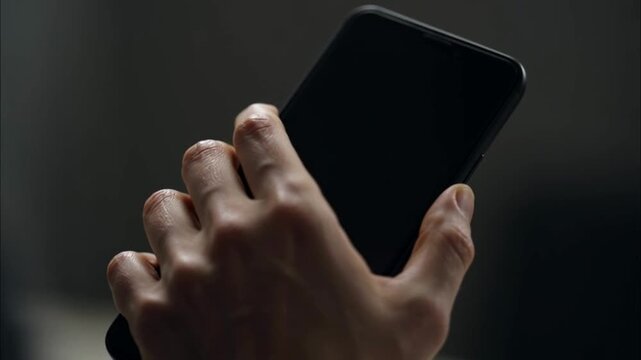 Hand holding a black smartphone device.
