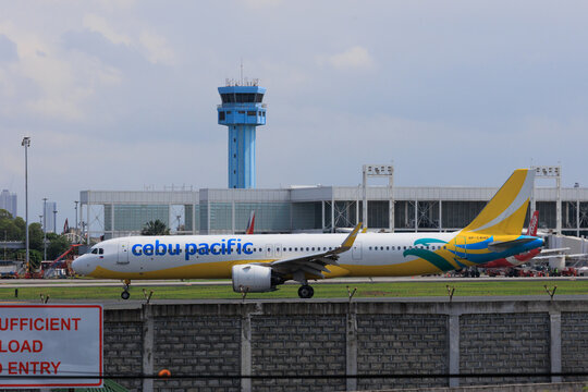 Manila, Metro Manila Philippines - 2025 July 13: A yellow and white commercial passenger jet taxiing on the runway