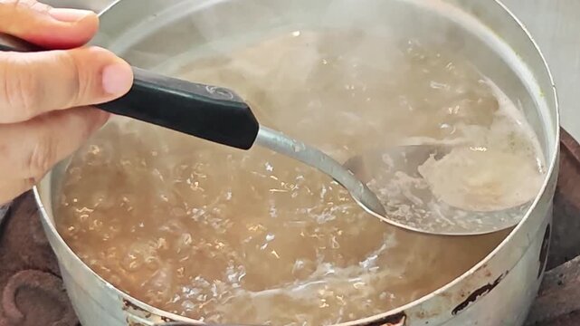 Removing impurities and fat foam from hot boiling pork soup.