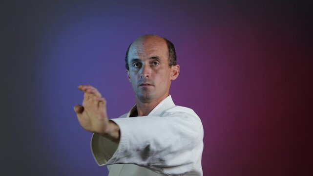 A young athlete practices punches and blocks with his hands against a multi-colored background with flashing lights.