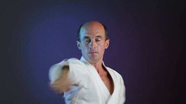 A young athlete performs punches and blocks with his hands against a multi-colored background with flashing lights