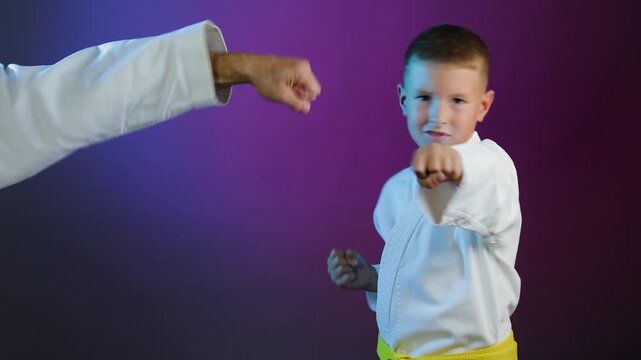 Young athlete and little boy athlete performing hand strikes on multi-colored background with flashing light