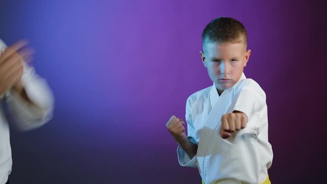 Young athlete and little boy athlete throw punches on colorful background with flashing light