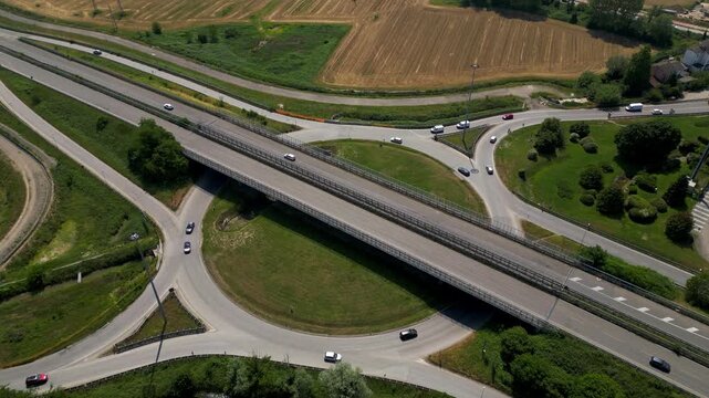 Highway intersection: Aerial shot capturing a modern highway intersection, designed for efficient traffic flow amidst a serene, green environment.