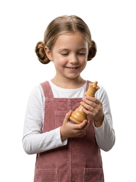 Isolated waist up young girl with hair buns wearing a pink pinafore looking at a large chess queen piece for a strategy game