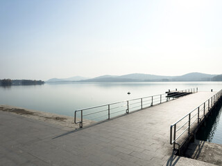 Obraz premium Tranquil Reflection: A Peaceful Lake Dock Under Misty Mountain Horizon