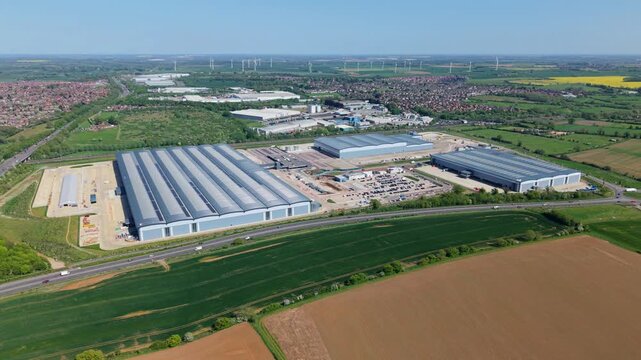 High angle drone tracking shot across a sprawling commercial fulfillment center in Northamptonshire