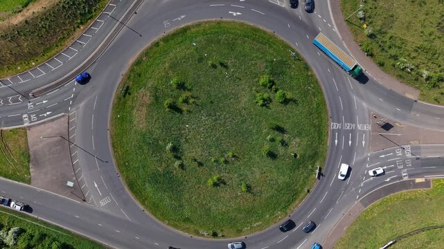 Time-lapse hyperlapse aerial top down view of traffic navigating a busy highway roundabout junction intersection.