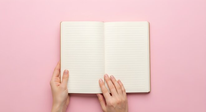 Open notebook with lined pages held by hands on a pink background