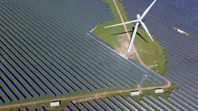 High angle perspective of a modern green energy hybrid park combining wind turbines and solar panels
