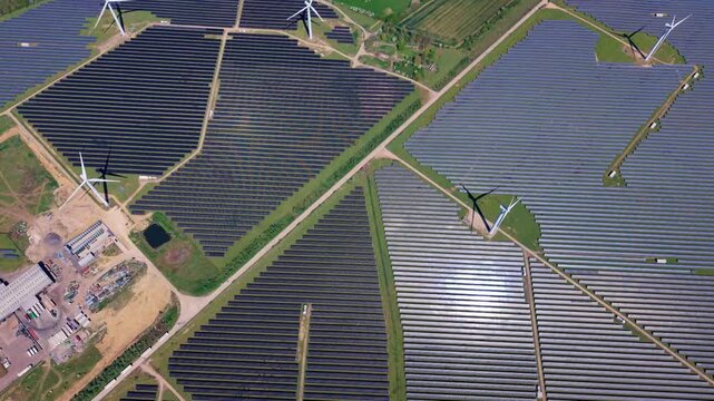 High angle perspective of a modern green energy hybrid park combining wind turbines and solar panels