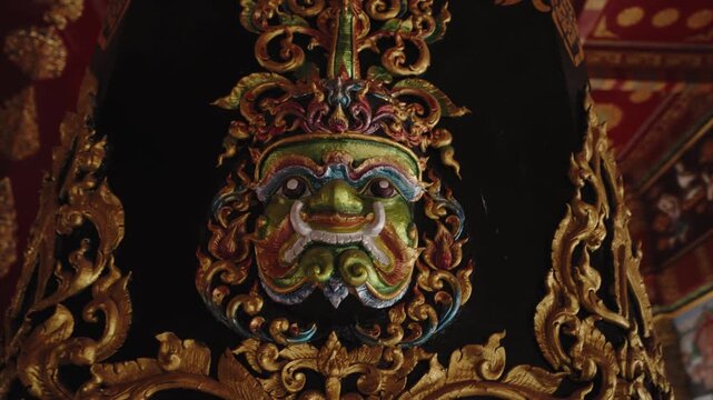 Intricate Close-up of a Mythical Yaksha Guardian Mask on an Ornate Pillar, Golden Bas-relief and Traditional Buddhist Art inside Wat Bang Thong Pagoda
