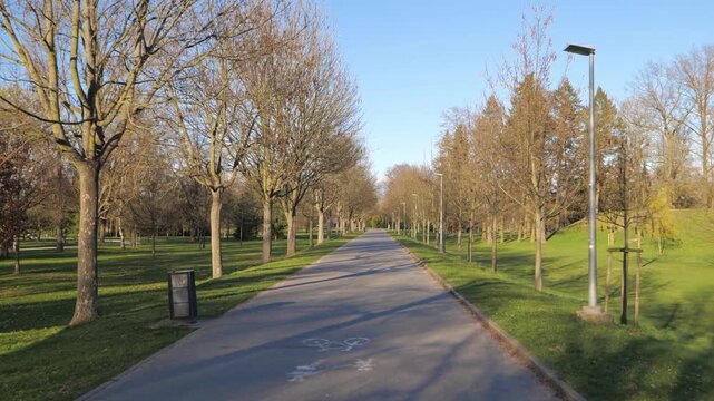 Empty paved pedestrian path through a public park with leafless trees in Hradec Kralove Czech Republic