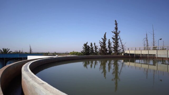 Wide panning shot of a circular clarifier tank and scraper mechanism at a water treatment plant. Ideal B-roll for projects covering municipal infrastructure, wastewater management, and sanitation.