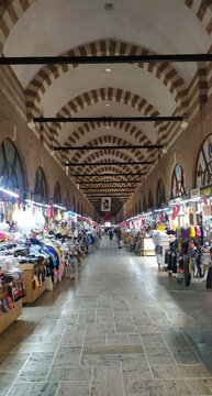 Historic Arasta Bazaar interior with repeating striped stone arches, Edirne, Turkey. Ottoman caravanserai architecture with market stalls.