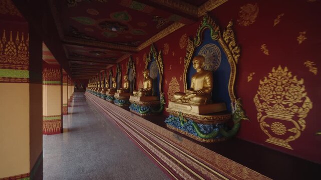 Serene POV Glide Past Endless Rows of Golden Buddha Statues in the Ornate Red Cloisters of Wat Bang Thong