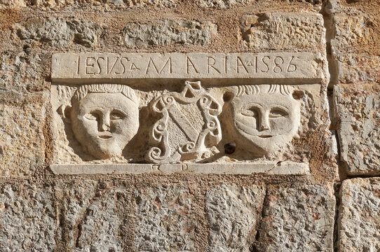 Stone relief, Latin text "IESVS MARIA 1586" (Jesus Mary 1586), two human faces. Budva, Montenegro.