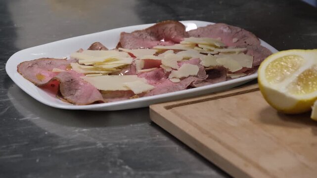 Preparazione di un piatto di roastbeef a fette. Condimento prima del servizio in una cucina di un ristorante