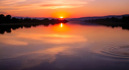 Obraz premium Dramatic sunset over calm water with city skyline silhouette