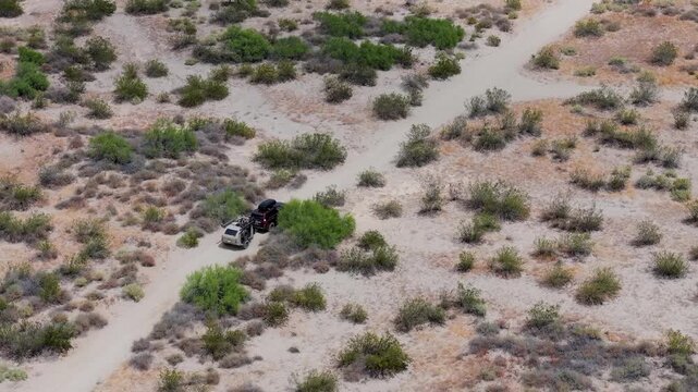 See an SUV pulling a teardrop trailer along dirt roads in Baja California Mexico surrounded by desert landscapes and greenery.