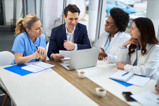 Mid adult businessman having a meeting with group of doctors in hospital