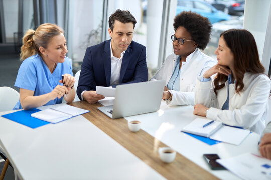 Mid adult businessman having a meeting with group of doctors in hospital