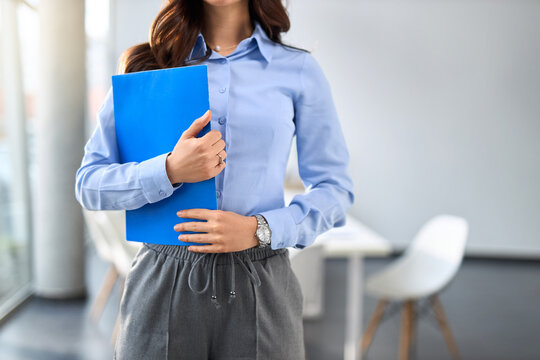 Close up of female entrepreneur holding blue clipboard in the office