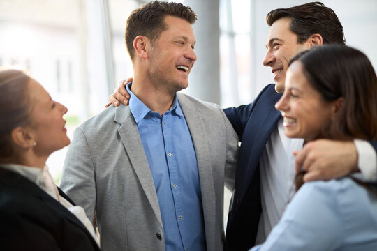 Group of happy entrepreneurs embracing in the office