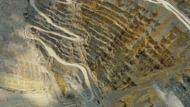 Aerial view of open pit copper ore mine and heavy mining equipment. Excavator and mining trucks in quarry, 4k