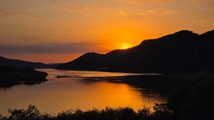 Fototapeta premium Sunset River Landscape with Forested Hills and Golden Reflection