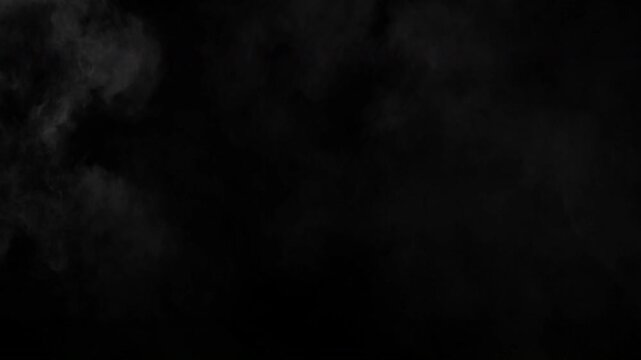 Abstract white smoke clouds slowly drifting on a dark black background creating a mysterious atmosphere.