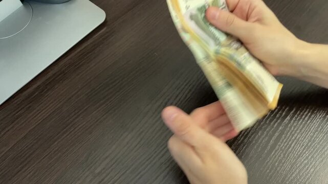 Hands sorting mixed banknotes on table, busy cashier organizing bills at checkout, quick flicking and fanning motion, retail counter context, bright lighting, focused closeup, transactional rhythm